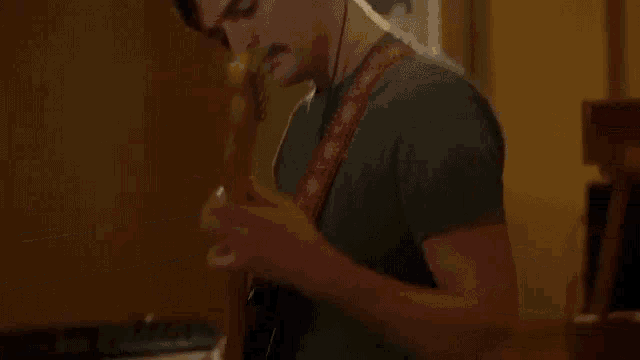 a man is playing a guitar in front of a piano in a recording studio .