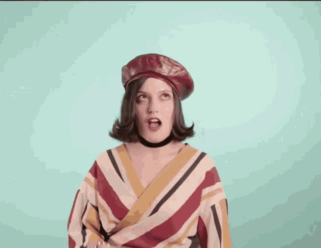 a woman wearing a red beret and a striped shirt is making a funny face