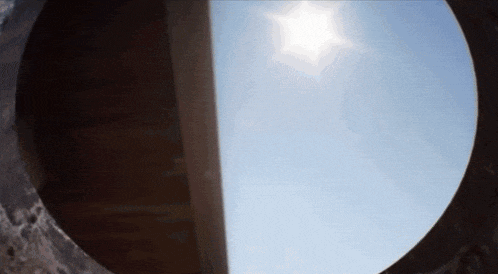 looking through a hole in a wall at the sun