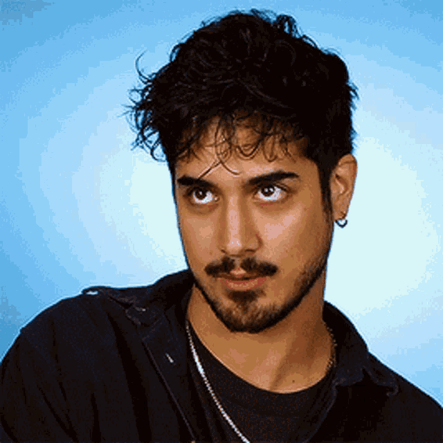 a man with curly hair and a beard is wearing earrings