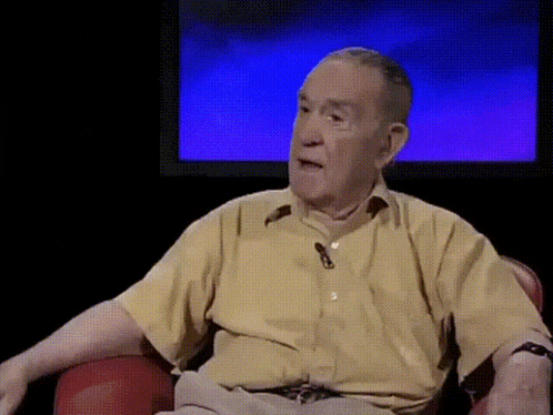 an elderly man in a yellow shirt is sitting in front of a blue screen