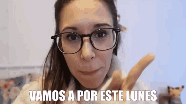 a woman wearing glasses says " vamos a por este lunes " in spanish