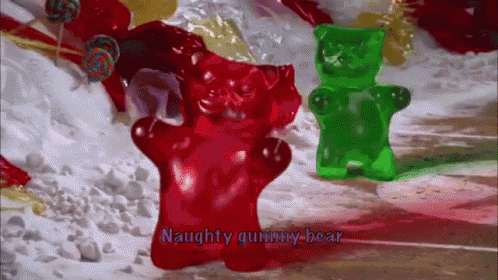 a red gummy bear and a green gummy bear are on a snowy surface