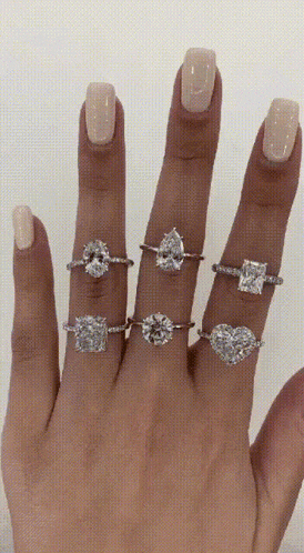 a woman 's hand with several rings on it
