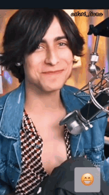 a man in a denim jacket is smiling in front of a microphone with the name astart_llano on the bottom right