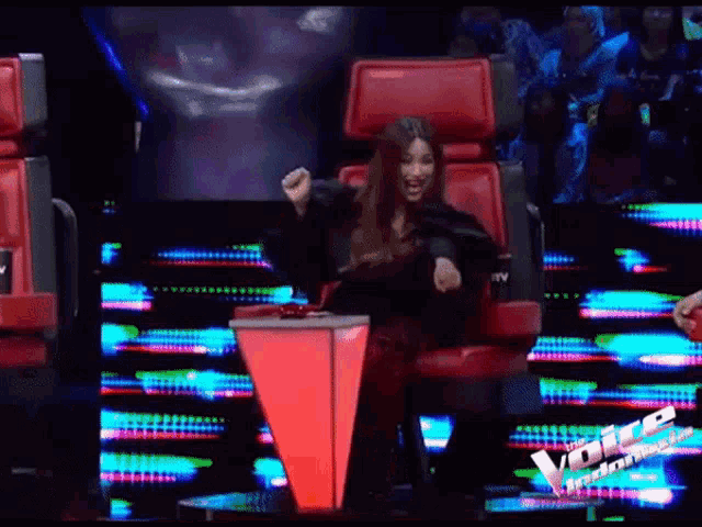 a woman sitting in a chair with a sign that says the voice