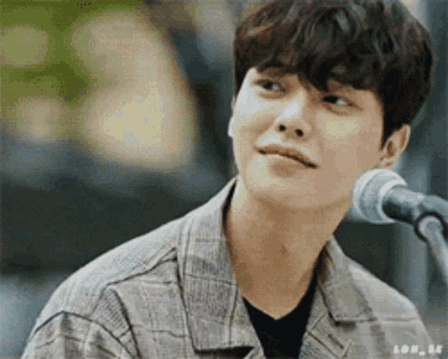 a young man is singing into a microphone while playing a guitar .