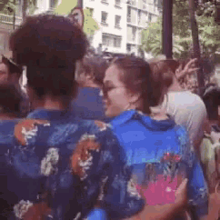 a woman in a blue shirt is hugging a man in a crowd