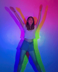 a woman is dancing in front of a rainbow wall