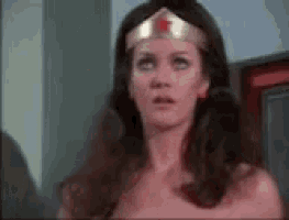a woman in a wonder woman costume is standing in front of a mirror .