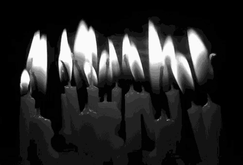 a row of lit candles in the dark