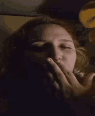 a woman is covering her mouth with her hand in a dark room