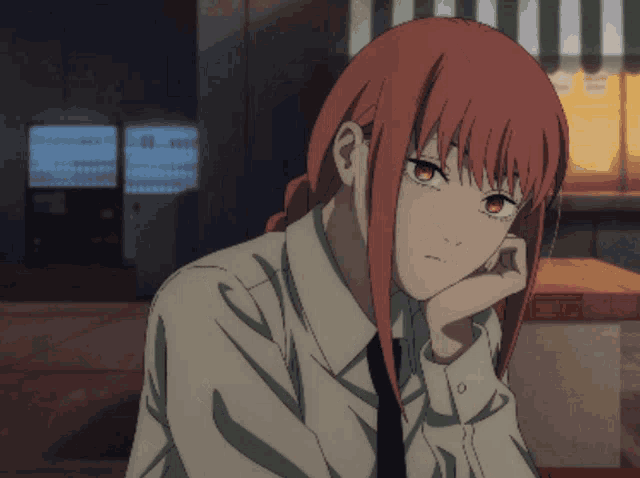 a girl with red hair is sitting at a table with her head resting on her hand