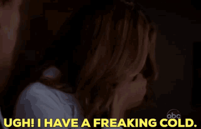 a woman covering her face with her hand while a man says " ugh i have a freaking cold "