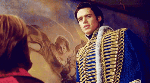 a man in a blue and gold military uniform is standing in front of a painting of a woman .