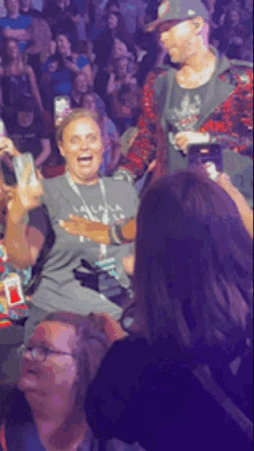 a woman in a gray shirt is laughing in a crowd of people