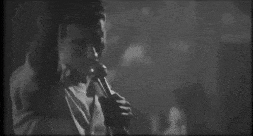 a black and white photo of a man holding a microphone .