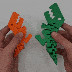 a person is holding a green and orange dinosaur toy in their hands