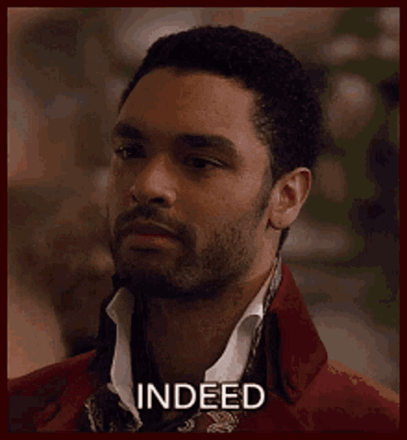 a man with a beard is wearing a red jacket and a scarf and the word indeed is on his face .