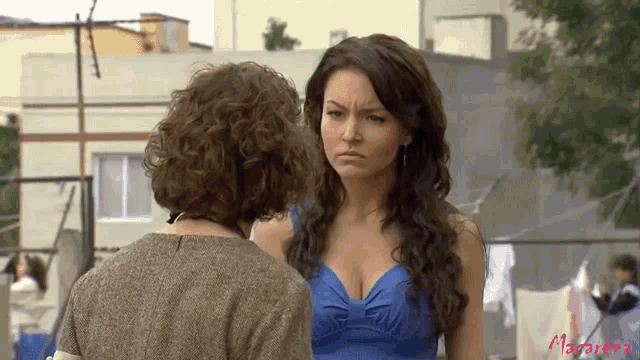 a woman in a blue dress stands next to another woman in a brown shirt