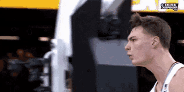 a basketball player is standing in front of a screen that says national championship .