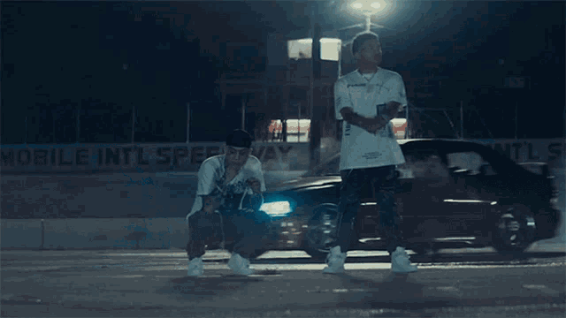 two men are squatting down in front of a sign that says mobile