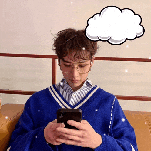 a person wearing glasses and a blue sweater is looking at their phone