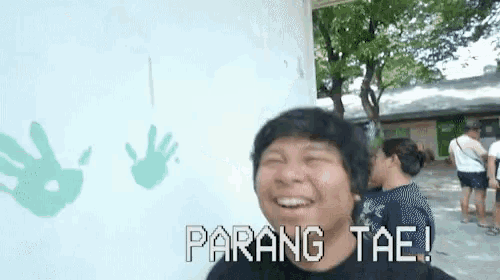 a man stands in front of a wall with handprints on it and the words parang tae