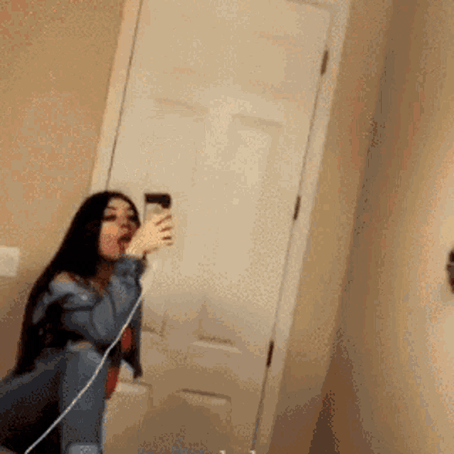 a woman is taking a selfie in front of a mirror in a bathroom .