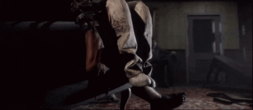 a person holding a knife in a dark room with blood on their pants