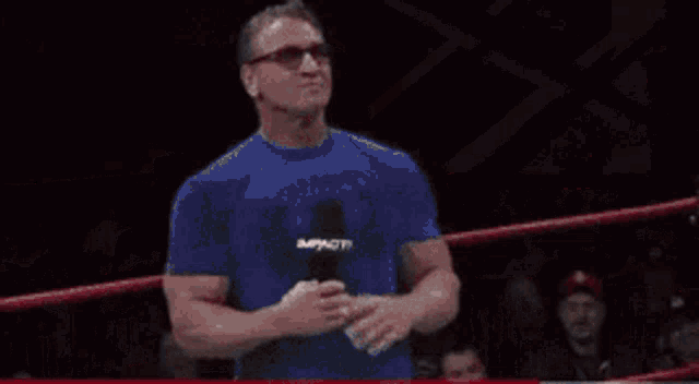 a man is standing in a wrestling ring wearing a white shirt
