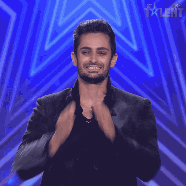 a man applauds in front of a star that says got talent on it
