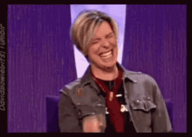 a man is laughing while wearing a gray jacket and a red tie