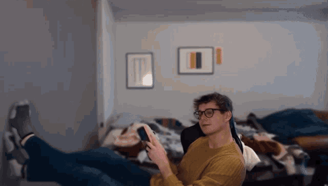 a man in a yellow sweater is reading a book in a bedroom