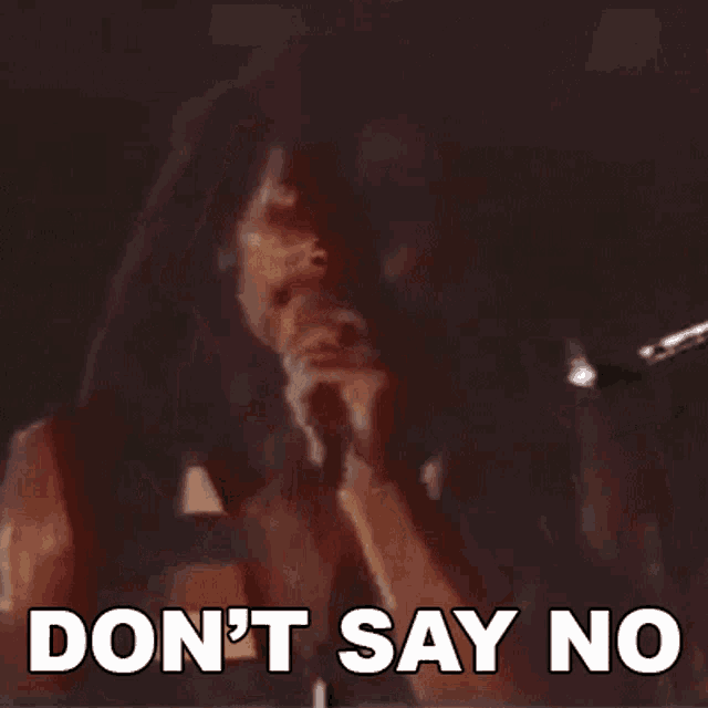a man singing into a microphone with the words " don 't say no " written below him