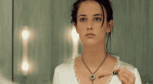 a woman looks at herself in a mirror while holding a key
