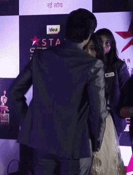 a man in a suit stands next to a woman in a white dress in front of a sign that says star