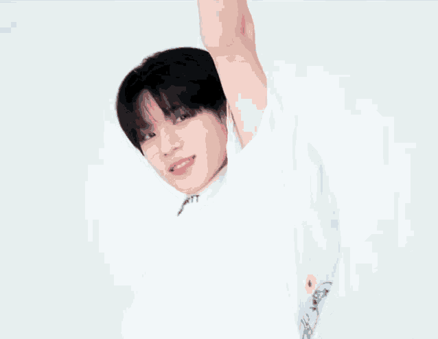 a young man with black hair is wearing a white t-shirt with his arm in the air .