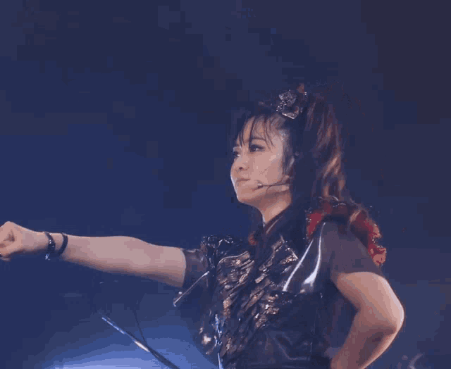 a woman with a microphone in her ear holds her fist up in the air