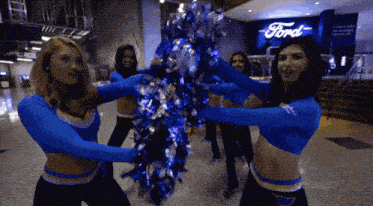 cheerleaders holding pom poms in front of a sign that says ford