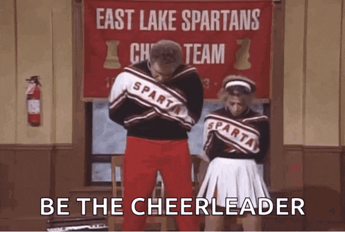 a man and a woman are standing next to each other in front of a sign that says east lake spartans cheerleading team .