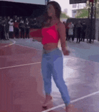 a woman is dancing on a basketball court while people watch .