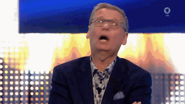 a man in a suit and glasses is making a funny face in front of a sign that says hd