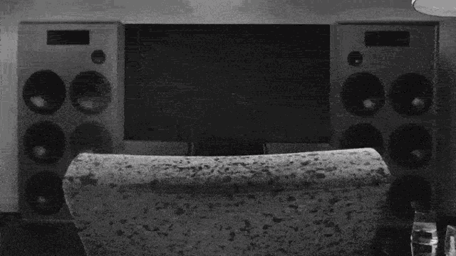 a black and white photo of a person sitting on a couch in front of a window .