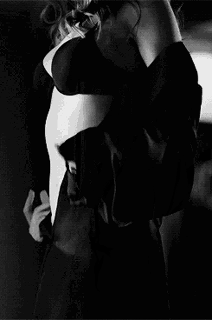 a black and white photo of a woman in a bra and skirt standing next to a wall with the number 20 on it .