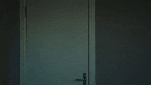 a man in a t-shirt is standing in a doorway