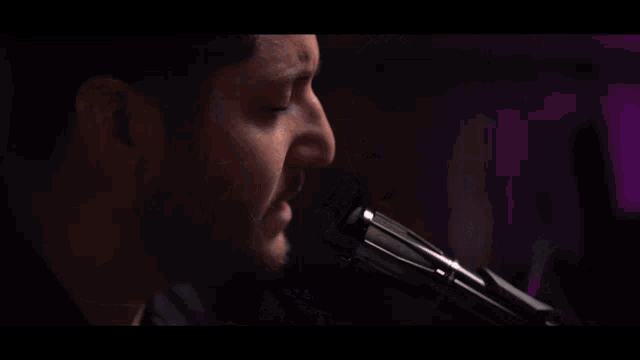 a man is singing into a microphone while playing a keyboard