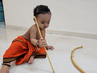 a baby is playing with a yellow stick on the floor