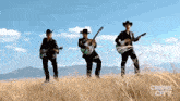 a group of cowboys are playing guitars in a field .