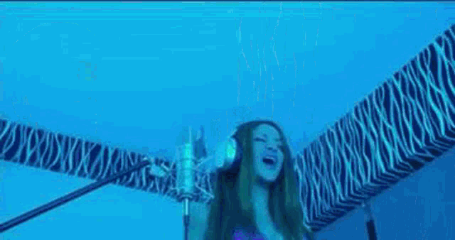 a woman is singing into a microphone in a blue room
